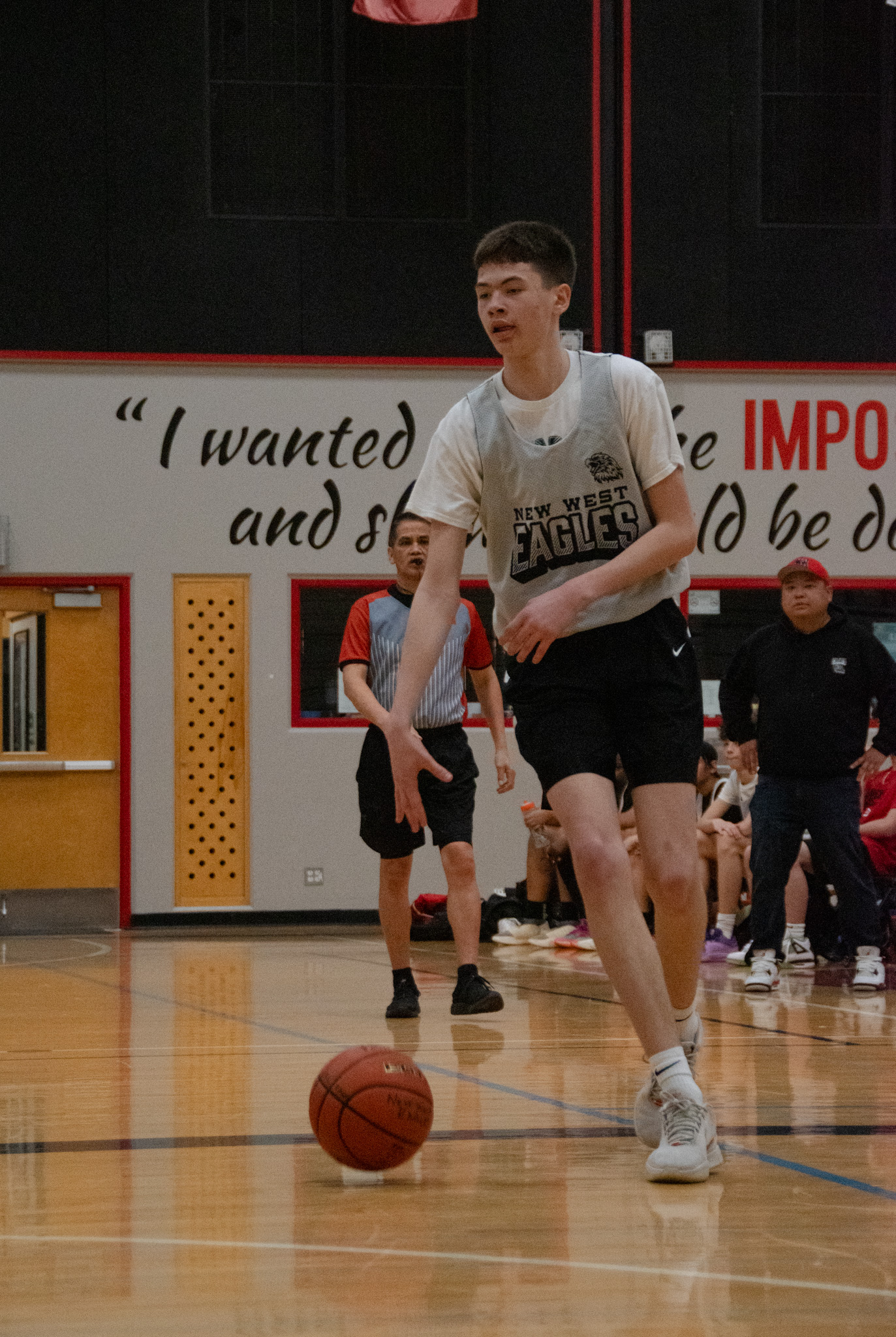 An Eagles player bringing the ball up the floor past a motivational gym wall